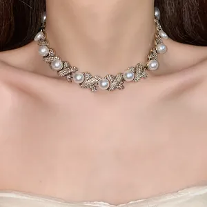 Detailed view of French retro necklace with rhinestone-encrusted crosses and white pearls