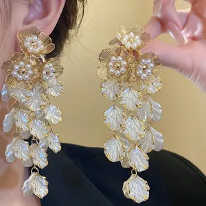 Vue détaillée macro de longues boucles d'oreilles fleuries à perles dorées