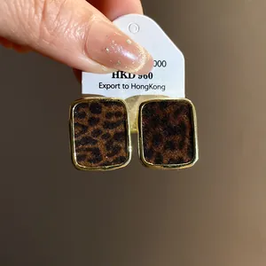 Gros plan détaillé de boucles d'oreilles vintage léopard floquées avec monture rectangulaire dorée.