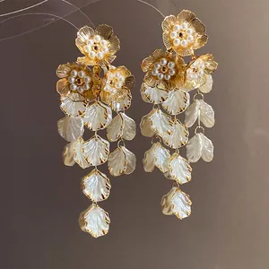 Gros plan d'élégantes boucles d'oreilles fleurs dorées avec perles et glands