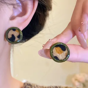 Boucles d'oreilles léopard rondes avec texture floquée et bordure verte.