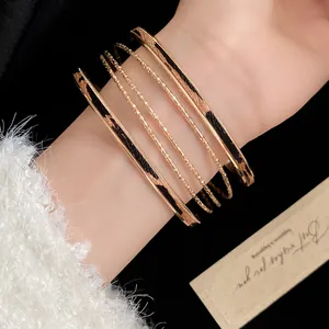 Close-up detail of trendy golden multi-layer bangle set with leopard print leather inlay