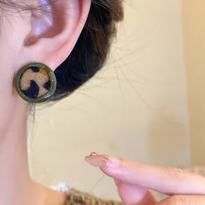 Gros plan d'une boucle d'oreille ronde vintage à motif léopard floqué sur l'oreille