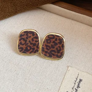 Détail de boucles d'oreilles vintage à imprimé léopard floqué avec bordure dorée