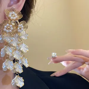 Gros plan de boucles d'oreilles à pampilles fleuries avec perles et feuilles blanches