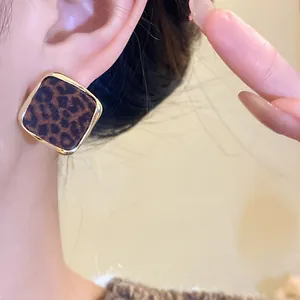 Vue rapprochée de boucles d'oreilles vintage à imprimé léopard et bordure dorée élégante.