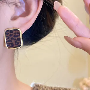 Détail d'une boucle d'oreille carrée à motif léopard floqué avec une monture dorée