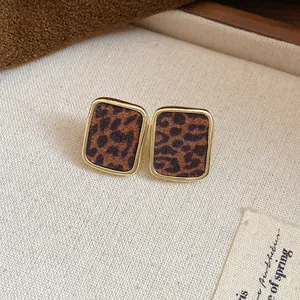 Détail macro de boucles d'oreilles rétro carrées avec finition léopard floquée