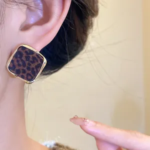 Détail d'une boucle d'oreille carrée vintage avec un motif léopard floqué et doré