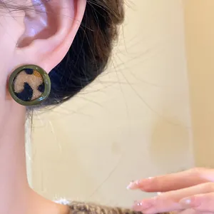 Vue détaillée de boucles d'oreilles vintage avec imprimé léopard floqué et bordure vert foncé