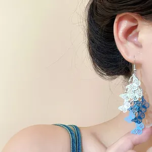 Primo piano di orecchini a nappa con farfalla blu e bianca indossati da un modello