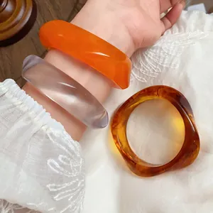 Detailed view of irregular marbled acrylic bracelets featuring retro orange and amber tones.