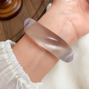 Close-up of a minimalist irregular translucent acrylic bangle showing smooth polished texture