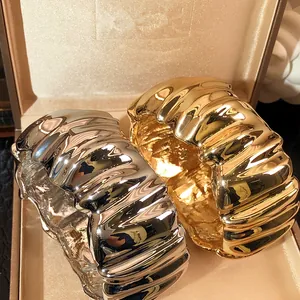 Close-up of gold and silver pleated wide bangles in luxury jewelry box