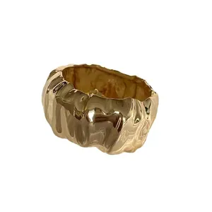 Elegant irregular wrinkled wide gold bangle with polished finish and minimalist style