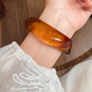 Macro detail of translucent amber acrylic irregular bangle with marble swirl texture