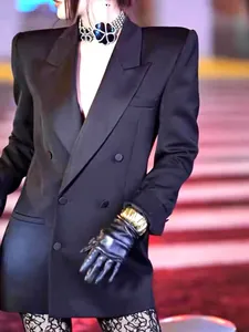 Close-up of an irregular wrinkled gold wide cuff bracelet worn on a black glove