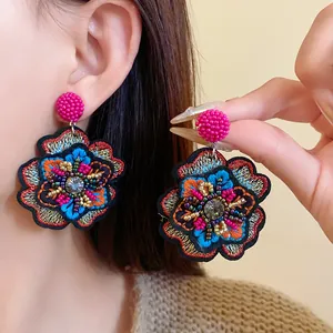 Detailed view of colorful vintage ethnic embroidered flower earrings with intricate beadwork