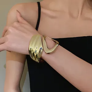 Macro detail of the gold irregular geometric hollow open cuff bracelet shown on a model