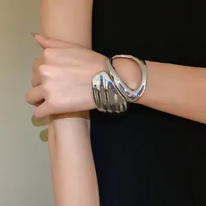 Close-up detail of a minimalist irregular geometric hollow cuff bracelet in polished silver