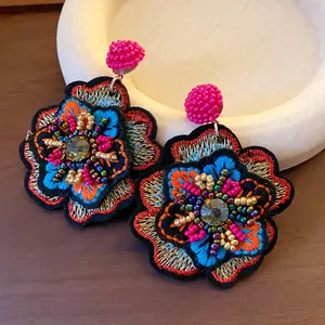Detailed macro shot of vintage embroidered flower earrings with colorful beads and crystals