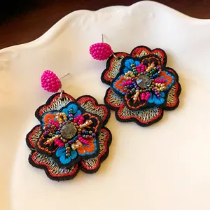 Detailed macro view of colorful handmade embroidered floral earrings with beads.