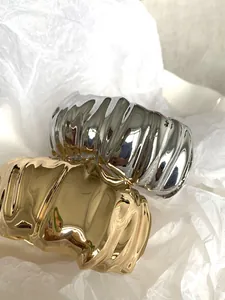 Chunky irregular pleated wide bangles in gold and silver finishes on white paper