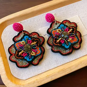 Close-up of vintage embroidered floral earrings with colorful beads and rhinestones