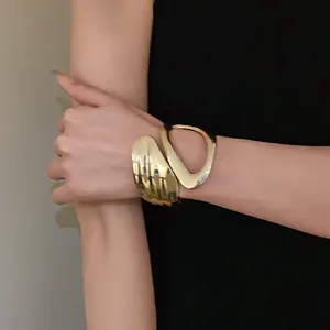 Detail shot of a minimalist gold irregular geometric hollowed-out cross open bracelet