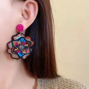Detailed view of vintage embroidered flower earrings with colorful beadwork and rhinestones