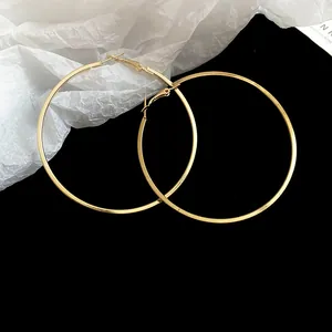 Detailed macro view of large gold-toned minimalist hoop earrings on a black background