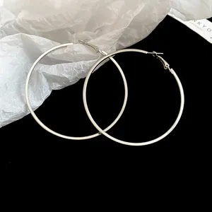 Detailed macro shot of minimalist large silver hoop earrings on a black background