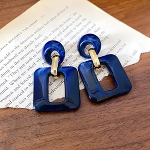Elegant blue marbled acrylic geometric drop earrings shown on vintage book page