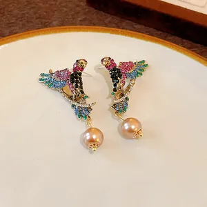 Detailed view of vintage style bird earrings with colorful rhinestones and faux pearls.
