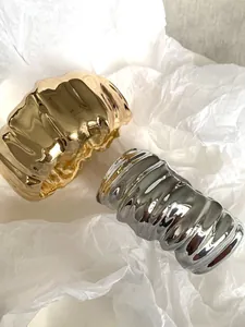 Detail view of irregular pleated wide cuff bracelets in gold and silver finishes.