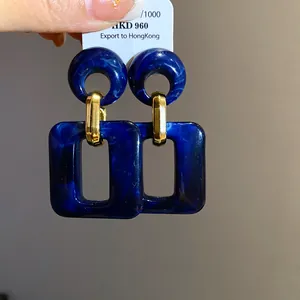 Detail view of blue marbled acrylic earrings with gold-tone links and rectangle drops.