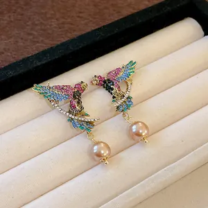 Detail of vintage bird wing charms with colorful rhinestones and faux pearls.