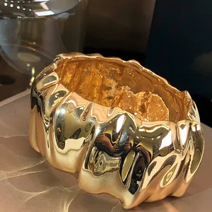Detailed view of a luxury gold pleated wide bangle with irregular sculptural texture