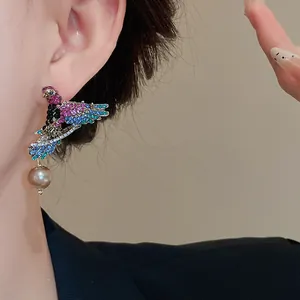 Detail view of vintage bird wing earring adorned with colorful crystals and a dangling pearl