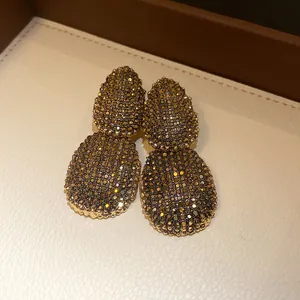Macro view of golden zircon earrings with intricate pave setting in a jewelry box