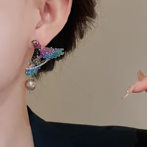 Close-up of vintage-style bird earring with colorful rhinestones and hanging pearl