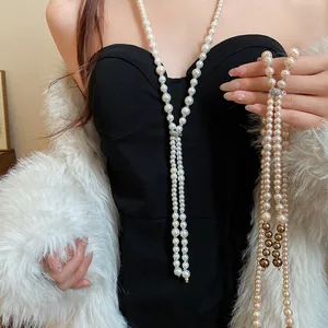 Detailed view of an elegant long fringe pearl necklace with rhinestone accents worn by a model