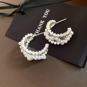 Macro view of elegant silver hoop earrings adorned with white pearls and zircons