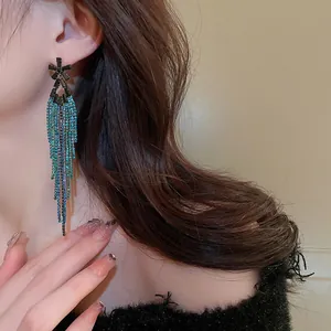 Elegant long tassel earrings with blue rhinestones on a female model for a chic look.