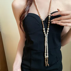 Elegant long tassel necklace featuring pearls and rhinestones on a stylish black dress.