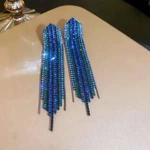 Detailed close-up of long tassel earrings with sparkling blue and teal rhinestone accents.