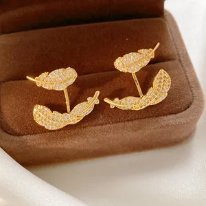 Detail shot of elegant gold-plated feather earrings encrusted with sparkling zirconia stones