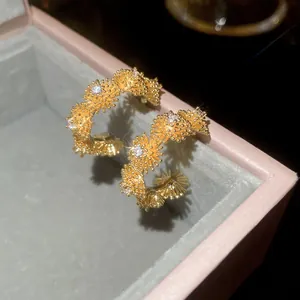Detailed shot of gold-toned firework textured hoop earrings with sparkling zircons