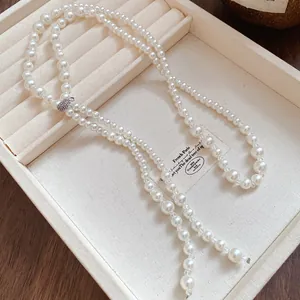 Elegant long pearl tassel necklace with sparkling diamond-encrusted buckle on tray