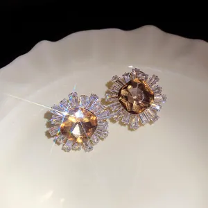 Close-up of sparkling amber sunburst earrings with brilliant light flare effect